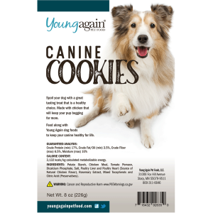 A package of Young Again Pet Food Canine Cookies featuring a happy, fluffy dog. The label highlights healthy ingredients, nutritional information, company details, and a warning about reproductive harm. Net weight: 8 oz (226g).